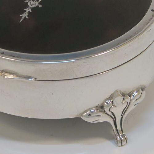 A very pretty Antique Sterling Silver and tortoise-shell jewellery box, having a plain round body, an in-laid tortoise-shell hinged lid, a cream coloured velvet-lined base, and sitting on three cast foliate feet. This beautiful silver and tortoise shell jewellery box was made by Synyer and Beddoes of Birmingham in 1919. The dimensions of this fine hand-made antique silver jewelery box are diameter 9 cms (3.5 inches), and height 4.5 cms (1.75 inches).