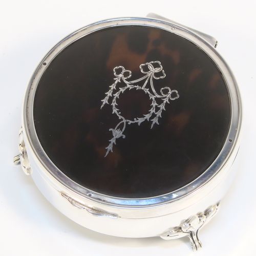 A very pretty Antique Sterling Silver and tortoise-shell jewellery box, having a plain round body, an in-laid tortoise-shell hinged lid, a cream coloured velvet-lined base, and sitting on three cast foliate feet. This beautiful silver and tortoise shell jewellery box was made by Synyer and Beddoes of Birmingham in 1919. The dimensions of this fine hand-made antique silver jewelery box are diameter 9 cms (3.5 inches), and height 4.5 cms (1.75 inches).