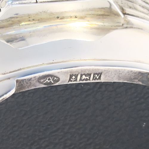 A small but elegant Sterling Silver jewelery box, having a plain oval-shaped body with straight sides, a slightly domed hinged lid with an applied Chippendale border and engine-turned engraved decoration, a gold gilt and red velvet-lined interior, and all sitting on four flanged feet. This beautiful silver jewellery box was made by the Adie Brothers of Birmingham in 1962. The dimensions of this fine hand-made antique silver jewellery box are length 7.5 cms (3 inches), width 6 cms (2.3 inches), and height 4 cms (1.5 inches)