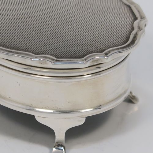 A small but elegant Sterling Silver jewelery box, having a plain oval-shaped body with straight sides, a slightly domed hinged lid with an applied Chippendale border and engine-turned engraved decoration, a gold gilt and red velvet-lined interior, and all sitting on four flanged feet. This beautiful silver jewellery box was made by the Adie Brothers of Birmingham in 1962. The dimensions of this fine hand-made antique silver jewellery box are length 7.5 cms (3 inches), width 6 cms (2.3 inches), and height 4 cms (1.5 inches)