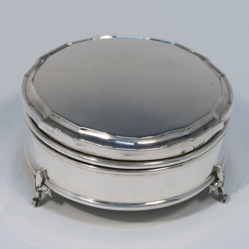 A very handsome Antique Sterling Silver jewelery box, having a plain round straight-sided body, a plain slightly domed hinged lid with a Bath edge style shaped border, a gold gilt and green satin-lined interior, and all sitting on three fleur-de-lis style feet. This elegant antique silver jewellery box was made by Goldsmiths and Silversmiths of London in 1912. The dimensions of this fine hand-made antique silver jewellery box are diameter 8.5 cms (3.3 inches), and height 4 cms (1.5 inches)   