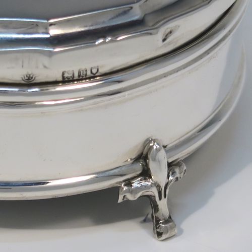 A very handsome Antique Sterling Silver jewelery box, having a plain round straight-sided body, a plain slightly domed hinged lid with a Bath edge style shaped border, a gold gilt and green satin-lined interior, and all sitting on three fleur-de-lis style feet. This elegant antique silver jewellery box was made by Goldsmiths and Silversmiths of London in 1912. The dimensions of this fine hand-made antique silver jewellery box are diameter 8.5 cms (3.3 inches), and height 4 cms (1.5 inches)