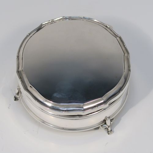 A very handsome Antique Sterling Silver jewelery box, having a plain round straight-sided body, a plain slightly domed hinged lid with a Bath edge style shaped border, a gold gilt and green satin-lined interior, and all sitting on three fleur-de-lis style feet. This elegant antique silver jewellery box was made by Goldsmiths and Silversmiths of London in 1912. The dimensions of this fine hand-made antique silver jewellery box are diameter 8.5 cms (3.3 inches), and height 4 cms (1.5 inches)