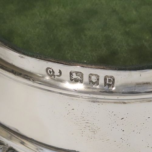 A very elegant Antique Sterling Silver jewelery box, having a plain oval-shaped body with straight sides, a slightly domed hinged lid with an applied pear and bead top border, a gold gilt and green velvet-lined interior, and all sitting on four flanged feet. This handsome silver jewellery box was made by Charles Edwards of London in 1918. The dimensions of this fine hand-made antique silver jewellery box are width 9 cms (3.5 inches), depth 6.5 cms (2.5 inches), and height 4.5 cms (1.75 inches)