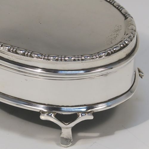 A very elegant Antique Sterling Silver jewelery box, having a plain oval-shaped body with straight sides, a slightly domed hinged lid with an applied pear and bead top border, a gold gilt and green velvet-lined interior, and all sitting on four flanged feet. This handsome silver jewellery box was made by Charles Edwards of London in 1918. The dimensions of this fine hand-made antique silver jewellery box are width 9 cms (3.5 inches), depth 6.5 cms (2.5 inches), and height 4.5 cms (1.75 inches)