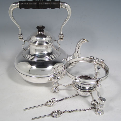 Sterling silver tea kettle on a burner stand, having a plain round baluster body with reeded decoration, a lift-off lid with wooden finial, a hinged handle with wooden insert, and sitting on an original burner stand with retaining pins and three cast hoof feet. Made by Robert Comyns of London in 1929. The dimensions of this fine silver kettle are length 21 cms (8.25 inches), height 28 cms (11 inches), width 14.5 cms (5.75 inches), and the total weight is approx. 1,000g (32 troy ounces).