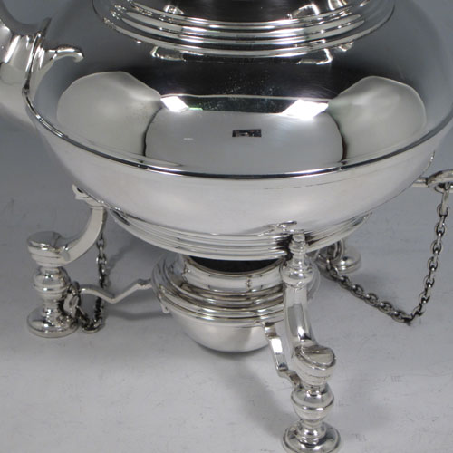 Sterling silver tea kettle on a burner stand, having a plain round baluster body with reeded decoration, a lift-off lid with wooden finial, a hinged handle with wooden insert, and sitting on an original burner stand with retaining pins and three cast hoof feet. Made by Robert Comyns of London in 1929. The dimensions of this fine silver kettle are length 21 cms (8.25 inches), height 28 cms (11 inches), width 14.5 cms (5.75 inches), and the total weight is approx. 1,000g (32 troy ounces).