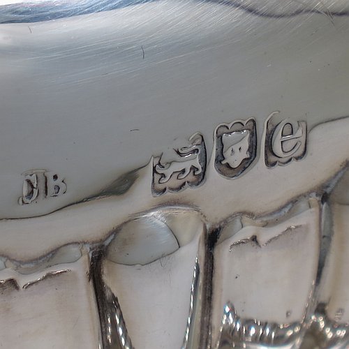 An Antique Victorian Sterling Silver tea kettle on a burner stand, having a Georgian Regency style rectangular bellied body with applied gadroon & shell borders and hand-chased fluted decoration, together with a hinged domed lid, an insulated silver handle and finial, and sitting on an original burner stand with four fluted lions-paw feet. Made by Charles Boyton of London in 1900. The dimensions of this fine hand-made antique silver kettle are length 24 cms (9.5 inches), height 33 cms (13 inches), width 15 cms (6 inches), and the total weight is approx. 1,056g (34 troy ounces).