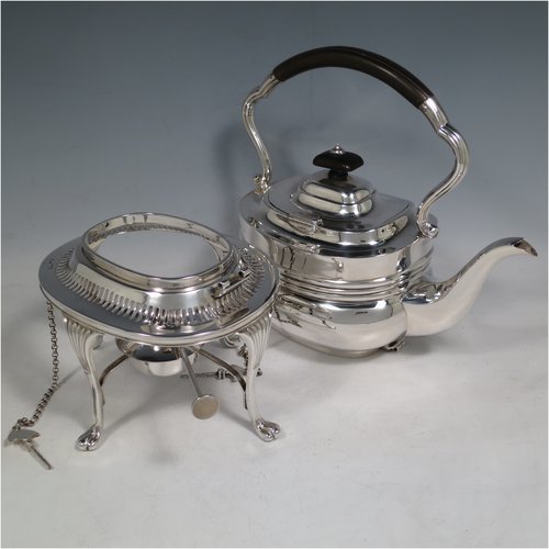 An Antique Edwardian Sterling Silver tea kettle on a burner stand, having a Georgian style rectangular baluster body, with a hinged domed lid, an insulated wooden handle and finial, and sitting on an original burner stand with a pierced border and four fluted feet. Made by Mappin & Webb of Sheffield in 1903. The dimensions of this fine hand-made antique silver kettle are length 23 cms (9 inches), height 33 cms (13 inches), width 15 cms (6 inches), and the total weight is approx. 1,145g (37 troy ounces).