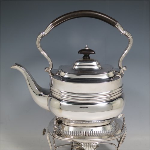 An Antique Edwardian Sterling Silver tea kettle on a burner stand, having a Georgian style rectangular baluster body, with a hinged domed lid, an insulated wooden handle and finial, and sitting on an original burner stand with a pierced border and four fluted feet. Made by Mappin & Webb of Sheffield in 1903. The dimensions of this fine hand-made antique silver kettle are length 23 cms (9 inches), height 33 cms (13 inches), width 15 cms (6 inches), and the total weight is approx. 1,145g (37 troy ounces).