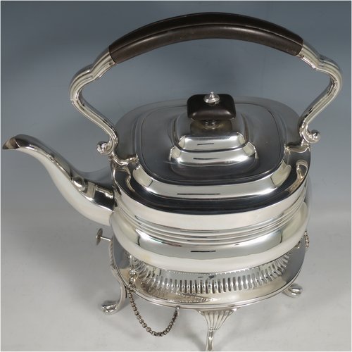 An Antique Edwardian Sterling Silver tea kettle on a burner stand, having a Georgian style rectangular baluster body, with a hinged domed lid, an insulated wooden handle and finial, and sitting on an original burner stand with a pierced border and four fluted feet. Made by Mappin & Webb of Sheffield in 1903. The dimensions of this fine hand-made antique silver kettle are length 23 cms (9 inches), height 33 cms (13 inches), width 15 cms (6 inches), and the total weight is approx. 1,145g (37 troy ounces).