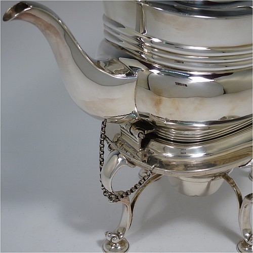 An Antique Edwardian Sterling Silver tea kettle on a burner stand, having a Georgian style rectangular baluster body, with a hinged domed lid, an insulated wooden handle and finial, and sitting on an original burner stand and four cast foliate feet. Made by Fordham and Faulkner of Sheffield in 1905. The dimensions of this fine hand-made antique silver kettle are length 23.5 cms (9.5 inches), height 33 cms (13 inches), width 15 cms (6 inches), and the total weight is approx. 1,350g (43.5 troy ounces).