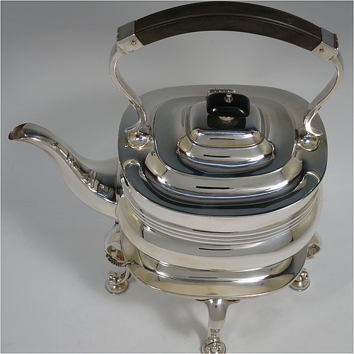 An Antique Edwardian Sterling Silver tea kettle on a burner stand, having a Georgian style rectangular baluster body, with a hinged domed lid, an insulated wooden handle and finial, and sitting on an original burner stand and four cast foliate feet. Made by Fordham and Faulkner of Sheffield in 1905. The dimensions of this fine hand-made antique silver kettle are length 23.5 cms (9.5 inches), height 33 cms (13 inches), width 15 cms (6 inches), and the total weight is approx. 1,350g (43.5 troy ounces).
