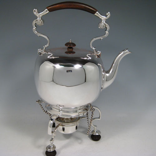 Antique Victorian sterling silver kettle on a burner stand in an early George I style, having a very plain round body, with wooden insulated scroll handle, a plain spout, a hinged lid with invisible hinge and wooden finial, and all sitting on a frame with original burner and securing pins with chains. All made by Thomas and Walter Slater of London in 1895. The dimensions of this fine hand-made silver kettle are height 32 cms (12.5 inches), length 21 cms (8.25 inches), and it weighs approx. 1,178g (38 troy ounces).  