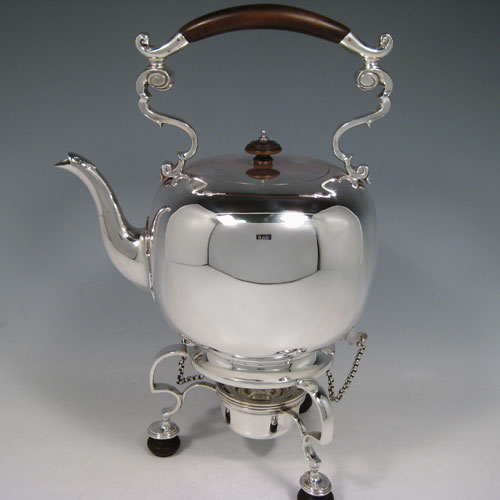 Antique Victorian sterling silver kettle on a burner stand in an early George I style, having a very plain round body, with wooden insulated scroll handle, a plain spout, a hinged lid with invisible hinge and wooden finial, and all sitting on a frame with original burner and securing pins with chains. All made by Thomas and Walter Slater of London in 1895. The dimensions of this fine hand-made silver kettle are height 32 cms (12.5 inches), length 21 cms (8.25 inches), and it weighs approx. 1,178g (38 troy ounces).