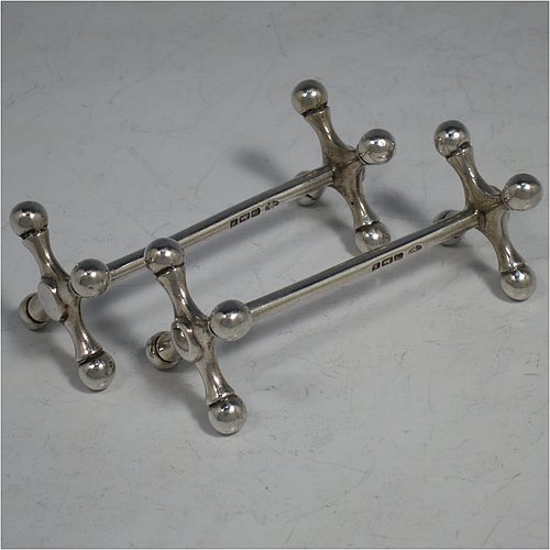 An Antique Edwardian Sterling Silver pair of knife rests, with traditional cast Jack-style rest ends, and plain round central struts. Made by William Hutton & Sons of Sheffield in 1910. The dimensions of this fine hand-made pair of antique silver knife rests are length 8 cms (3 inches), height 3 cms (1.25 inches), and they weigh a total of approx. 101g (3.3 troy ounces).    