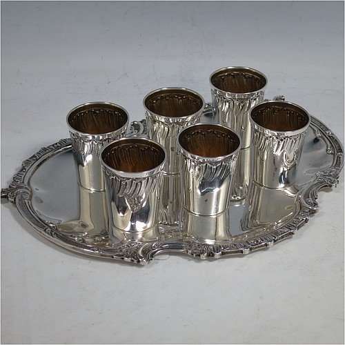 An Antique Victorian French First Quality Standard (950 std) sterling silver set of six liqueor tots / measures and original serving salver, the tots having round straight-sided bodies with gold-gilt interiors and hand-chased swirl-fluted upper borders, the salver with a plain ground and an applied cast foliate border. Made in France in ca. 1890. The dimensions of this fine hand-made antique silver liqueur set are height of tots 4 cms (1.5 inches), length of serving tray 20 cms (8 inches), and the total weight is approx. 285g (9.2 troy ounces).   