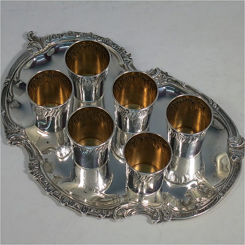 An Antique Victorian French First Quality Standard (950 std) sterling silver set of six liqueor tots / measures and original serving salver, the tots having round straight-sided bodies with gold-gilt interiors and hand-chased swirl-fluted upper borders, the salver with a plain ground and an applied cast foliate border. Made in France in ca. 1890. The dimensions of this fine hand-made antique silver liqueur set are height of tots 4 cms (1.5 inches), length of serving tray 20 cms (8 inches), and the total weight is approx. 285g (9.2 troy ounces).