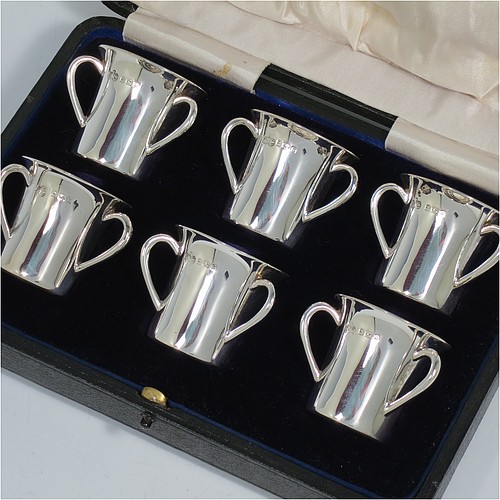An Antique Edwardian Sterling Silver set of six liqueor tots or measures, round straight-sided bodies with three loop side-handles, all in their original cream satin and dark blue velvet-lined presentation box. Made by Elkington and Co., of Birmingham in 1909. The dimensions of this fine hand-made antique silver liqueur set are height 4 cms (1.5 inches), diameter 4 cms (1.5 inches), and the total weight is approx. 195g (6.3 troy ounces).