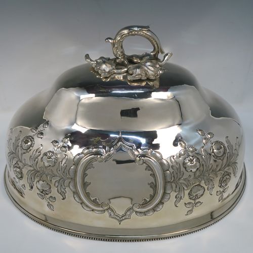 A beautiful Antique Victorian Silver Plated meat cover dome, having an oval domed body with hand-chased floral decoration surrounding two vacant cartouches on both sides, a cast floral loop handle, and an applied bead-edged bottom border. This stunning silver-plated meat cover was made in ca. 1870. The dimensions of this fine hand-made antique silver-plated meat cover dome are length 47 cm (18.5 inches), width 35.5 cms (14 inches), and height 28 cms (11 inches).   