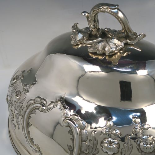 A beautiful Antique Victorian Silver Plated meat cover dome, having an oval domed body with hand-chased floral decoration surrounding two vacant cartouches on both sides, a cast floral loop handle, and an applied bead-edged bottom border. This stunning silver-plated meat cover was made in ca. 1870. The dimensions of this fine hand-made antique silver-plated meat cover dome are length 47 cm (18.5 inches), width 35.5 cms (14 inches), and height 28 cms (11 inches).   