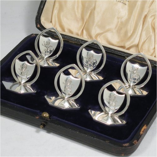 An Antique Sterling Silver set of six place card holders, having shield-shaped bodies, each mounted in a pointed ring on an octagonal base, and all in their original satin and velvet-lined presentation box. Made by William Hutton of London in 1912. The dimensions of this fine set of antique silver place card holders are width of bases 3.5 cms (1.25 inches), height 3 cms (1.25 inches), and they weigh a total of approx. 140g (4.5 troy ounces). Please note that each on is engraved with a rampant lion.