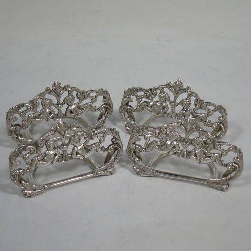 A very pretty Antique Victorian Sterling Silver set of four place card holders, having cast bodies with reclining cherubs over scroll and floral decoration, and sitting on half-circle wire-work bases. Made by Samuel Jacob of London in 1894. The dimensions of this fine set of antique silver place card holders are width 7 cms (2.75 inches), height 4 cms (1.5 inches), depth 3 cms (1.25 inches), and they weigh a total of approx. 106g (3.4 troy ounces).   