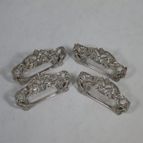 A very pretty Antique Victorian Sterling Silver set of four place card holders, having cast bodies with reclining cherubs over scroll and floral decoration, and sitting on half-circle wire-work bases. Made by Samuel Jacob of London in 1894. The dimensions of this fine set of antique silver place card holders are width 7 cms (2.75 inches), height 4 cms (1.5 inches), depth 3 cms (1.25 inches), and they weigh a total of approx. 106g (3.4 troy ounces).