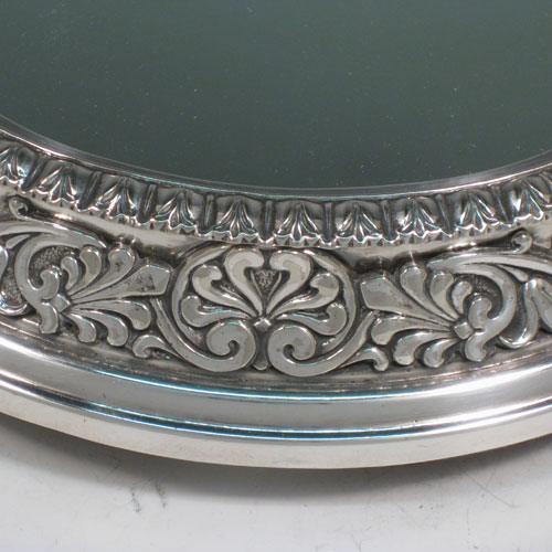 Antique Victorian silver-plated mirror plateau, having a very unusual tri-lobed shaped body, applied floral and scroll borders, and an original oak base with three hinged feet for ease of cleaning. Made by Elkington and Co., with their date letter for 1873. The dimensions of this fine hand-made mirror plateau are width 34 cms (13.5 inches), and height 5 cms (2 inches).