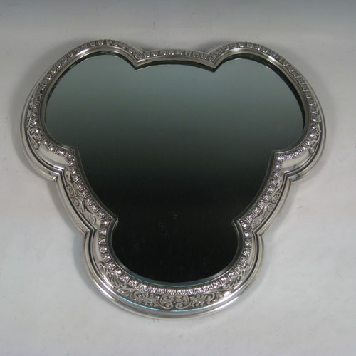 Antique Victorian silver-plated mirror plateau, having a very unusual tri-lobed shaped body, applied floral and scroll borders, and an original oak base with three hinged feet for ease of cleaning. Made by Elkington and Co., with their date letter for 1873. The dimensions of this fine hand-made mirror plateau are width 34 cms (13.5 inches), and height 5 cms (2 inches).