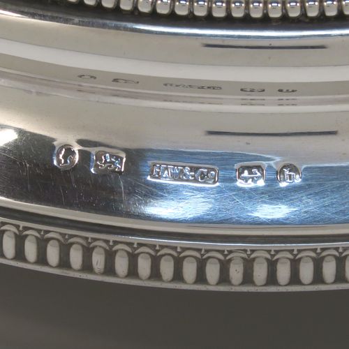 A very pretty Antique Victorian Sterling Silver mirror plateau, having a round body with an applied bead-edged top border surrounding the mirror, an applied gadroon-edged bottom border, all sitting on three cast foliate and shell feet, and an original oak base underneath. This elegant antique silver mirror plateau was made by Henry Woodward of Birmingham in 1876. The dimensions of this fine hand-made antique silver mirror plateau are diameter 29 cms (11.5 inches), and height 6 cms (2.3 inches).