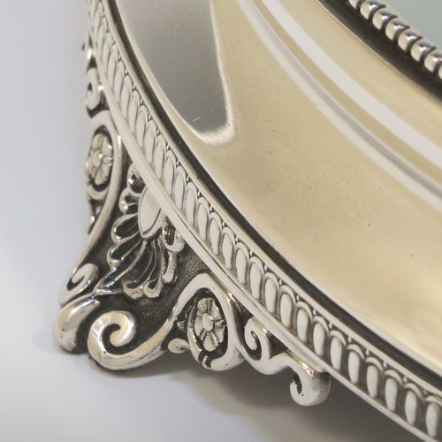 A very pretty Antique Victorian Sterling Silver mirror plateau, having a round body with an applied bead-edged top border surrounding the mirror, an applied gadroon-edged bottom border, all sitting on three cast foliate and shell feet, and an original oak base underneath. This elegant antique silver mirror plateau was made by Henry Woodward of Birmingham in 1876. The dimensions of this fine hand-made antique silver mirror plateau are diameter 29 cms (11.5 inches), and height 6 cms (2.3 inches).