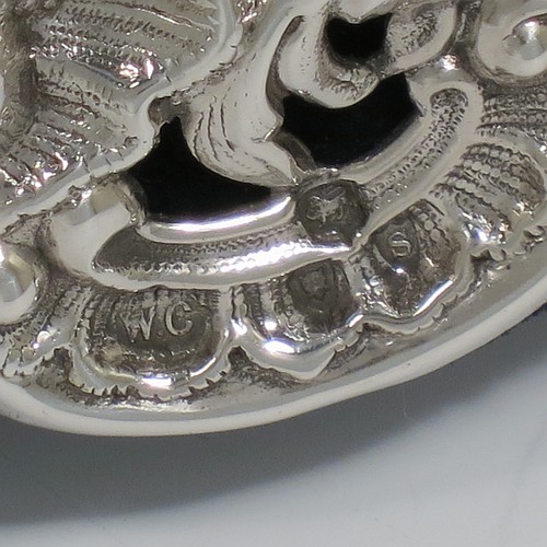 An Antique Victorian Sterling Silver table or vanity mirror having hand-chased cherubs and birds, scroll-work, and floral decoration, with a top vacant cartouche, an original bevelled heart-shaped mirror, and blue velvet backing with easel stand. Made by William Comyns of London in 1893. The dimensions across the frame of this fine hand-made antique silver vanity or table mirror are height 28 cms (11 inches), and width 24 cms (9.5 inches).