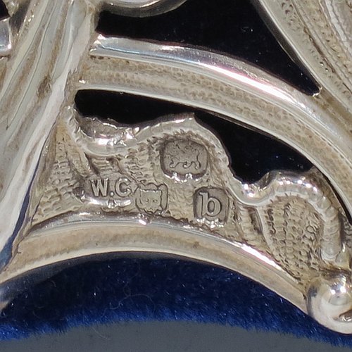 An Antique Victorian Sterling Silver table or vanity mirror having hand-chased birds, scroll-work, and floral decoration, with a top vacant cartouche, an original bevelled heart-shaped mirror, and blue velvet backing with easel stand. Made by William Comyns of London in 1897. The dimensions across the frame of this fine hand-made antique silver vanity or table mirror are height 28 cms (11 inches), and width 24 cms (9.5 inches).