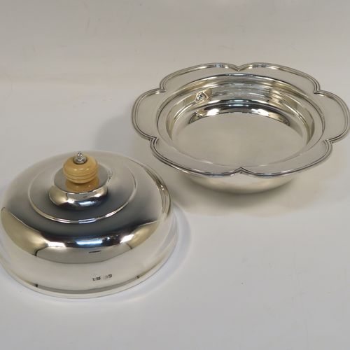 An elegant Sterling Silver muffin dish, having a round body with an applied and shaped reeded petal border, a domed lift-off lid with a bone finial, an original internal liner, and all sitting on a flat base. This beautiful silver caviar or muffin dish was made by Mappin and Webb of Sheffield in 1926. The dimensions of this fine hand-made silver muffin or caviar dish are diameter 18 cms (7 inches), height 10 cms (4 inches), and it weighs approx. 550g (17.7 troy ounces).