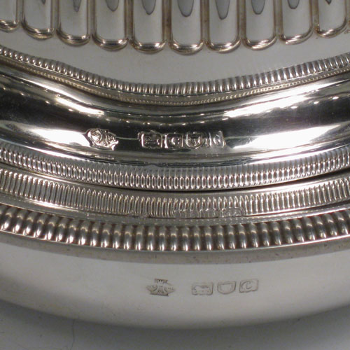 Antique Victorian sterling silver covered muffin dish, having a lift-off lid with half-fluted decoration and wooden finial, a removable plate (which can double as a serving dish) with a gadroon edge, and a deep base for hot water (or crushed ice) with two cast handles. Made by William Hutton and Sons of London in 1898. Height 15 cms (6 inches), diameter of removable plate 20 cms (8 inches). Total weight approx. 550g (17.7 troy ounces).