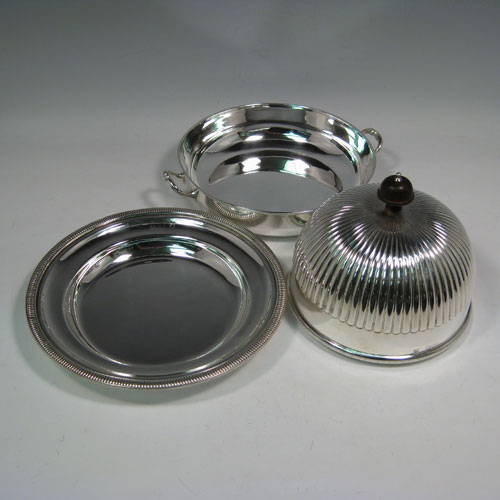 Antique Victorian sterling silver covered muffin dish, having a lift-off lid with half-fluted decoration and wooden finial, a removable plate (which can double as a serving dish) with a gadroon edge, and a deep base for hot water (or crushed ice) with two cast handles. Made by William Hutton and Sons of London in 1898. Height 15 cms (6 inches), diameter of removable plate 20 cms (8 inches). Total weight approx. 550g (17.7 troy ounces).
