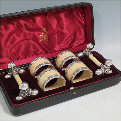 An Antique Victorian Silver-Plated and bone set of four napkin rings and two knife rests, the napkin rings having round straight-sided bodies with applied bands of floral decoration, the knife rests having cast floral supports with button ends, all in their original maroon satin and velvet-lined presentation box. Made by Elkington & Co., in ca. 1880. The dimensions of these fine hand-made antique silver plated and bone napkin rings are diameter 4.5 cms (1.75 inches), height 3 cms (1.25 inch), and the knife rests are 8.5 cms (3.3 inches) long by 4 cms (1.5 inches) high.    