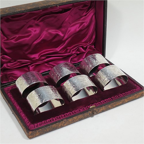 A very pretty Antique Victorian Sterling Silver set of six napkin rings, having oval-shaped bodies with straight sides and hand-engraved ferns and gingko leaves surrounding a cartouche on one side, all in their original maroon satin and velvet-lined presentation box. Made by Edward Hutton of London in 1891. The dimensions of these fine hand-made antique silver napkin rings are length 5 cms (2 inches), height 3 cms (1.25 inch), and they weigh a total of approx. 166g (5 troy ounces). Please note that these items are crested and numbered 1 to 6.   