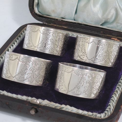 A very pretty Antique Victorian Sterling Silver set of four napkin rings, having round bodies with straight sides, hand-engraved floral and scroll decoration with two vacant shaped shield style cartouches, all in their original light blue satin and dark blue velvet-lined presentation box. Made by Walker and Hall of Sheffield in 1894. The dimensions of these fine hand-made antique silver-plated napkin rings are diameter 4.5 cms (1.75 inches), height 2.5 cms (1 inch), and they weigh a total of approx. 119g (3.8 troy ounces).