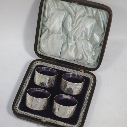 A very pretty Antique Victorian Sterling Silver set of four napkin rings, having round bodies with straight sides, hand-engraved floral and scroll decoration with two vacant shaped shield style cartouches, all in their original light blue satin and dark blue velvet-lined presentation box. Made by Walker and Hall of Sheffield in 1894. The dimensions of these fine hand-made antique silver-plated napkin rings are diameter 4.5 cms (1.75 inches), height 2.5 cms (1 inch), and they weigh a total of approx. 119g (3.8 troy ounces).