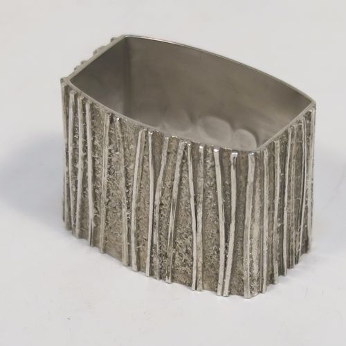 A very unusual Modernistic style Sterling Silver pair of napkin rings, having straight sided rectangular bodies with three sides having a cast bark-like finish, and the fourth side with large spread hallmarks including the Queens Jubilee mark. These beautiful silver napkin rings were made by Graham Watling of London in 1977. The dimensions of these fine hand-made silver napkin rings are length 4.5 cms (1.75 inches), height 3 cms (1.25 inches), and they weigh a total of approx. 93g (3 troy ounces).