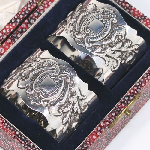 A very pretty Antique Victorian Sterling Silver pair of napkin rings, having round straight-sided bodies with hand-chased floral and scroll decoration surrounding an oval vacant cartouche on one side, all in their original cream satin and dark blue velvet-lined presentation box. These beautiful antique silver napkin rings were made by George Maudsley Jackson of London in 1898. The dimensions of these fine hand-made antique silver napkin rings are diameter 4.5 cms (1.75 inches), height 3 cms (1 inches), and they weigh a total of approx. 56g (1.8 troy ounces).