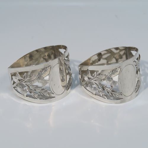 A very pretty Antique Art Nouveau style Sterling Silver pair of napkin rings, having semi-circular bodies with flat sides, with hand-pierced Scottish Thistle floral decoration, surrounding vacant oval cartouches. These beautiful antique silver napkin rings were made by Walker and Hall of Sheffield in 1911. The dimensions of these fine hand-made antique silver napkin rings are length 5 cms (2 inches), height 3.5 cms (1.3 inches), and they weigh a total of approx. 56g (1.8 troy ounces).