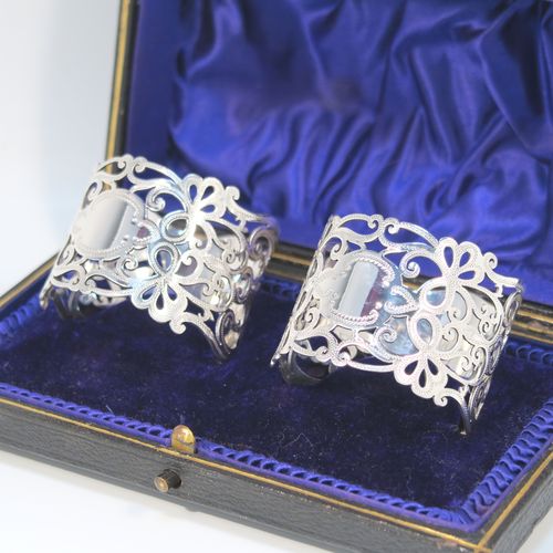 A very pretty Antique Edwardian Art Nouveau style Sterling Silver pair of napkin rings, having round straight-sided bodies with hand-pierced and engraved floral and scroll decoration, all in their original dark blue satin and velvet-lined presentation box. These beautiful antique silver napkin rings were made by George Rhoden of Sheffield in 1909. The dimensions of these fine hand-made antique silver napkin rings are diameter 4.5 cms (1.75 inches), height 4 cms (1.5 inches), and they weigh a total of approx. 63g (2 troy ounces).