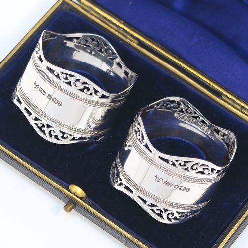 A very pretty Antique Edwardian Sterling Silver pair of napkin rings, having round straight-sided bodies, with hand-pierced scroll borders above two bands of bead work, all in their original dark blue satin and velvet-lined presentation box. These beautiful antique silver napkin rings were made by Roberts and Belk of Sheffield in 1903. The dimensions of these fine hand-made antique silver napkin rings are diameter 4.5 cms (1.75 inches), height 3.5 cms (1.3 inches), and they weigh a total of approx. 52g (1.6 troy ounces).