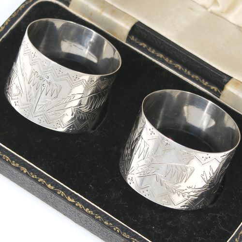 A very pretty pair of Aesthetic style Antique Victorian Sterling Silver napkin rings, having round straight-sided bodies with hand-engraved fern-work decoration and flying crane birds, and all in their original cream satin and black velvet-lined presentation box. These beautiful antique silver Aesthetic style napkin rings were made in London in 1876 and 1877. The dimensions of these fine hand-made antique silver napkin rings are diameter 4 cms (1.5 inches), height 3 cms (1 inch), and they weigh a total of approx. 51g (1.6 troy ounce).   