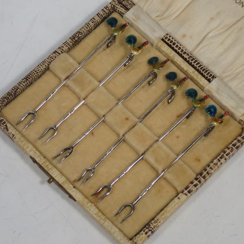 A very stylish Art Deco Sterling silver set of six cocktail sticks, having hand enamelled cockerel mounts and twin toasting fork style ends, all in their original cream satin and velvet-lined presentation box. Made by A. Scott of Birmingham in 1927. The dimensions of this fine hand-made antique silver set of cocktail sticks are length 8.5 cms (3.3 inches), and they weigh a total of approx. 16g (0.5 troy ounces).