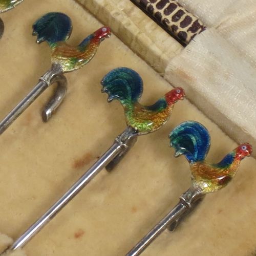 A very stylish Art Deco Sterling silver set of six cocktail sticks, having hand enamelled cockerel mounts and twin toasting fork style ends, all in their original cream satin and velvet-lined presentation box. Made by A. Scott of Birmingham in 1927. The dimensions of this fine hand-made antique silver set of cocktail sticks are length 8.5 cms (3.3 inches), and they weigh a total of approx. 16g (0.5 troy ounces).