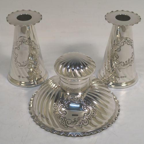 A very pretty Antique Victorian Sterling Silver desk set consisting of an inkstand and a pair of candle holders, in a round style with hand-chased swirl fluting and wavy-edge borders, the inkstand with a hinged lid and glass liner, the candlesticks with removable nozzles. This beautiful silver desk set was made by the Dixon Brothers of Sheffield in 1889. The dimensions of this fine antique silver desk set are height of candlesticks 14 cms (5.5 inches), and diameter of inkstand at base 11.5 cms (4.5 inches).  